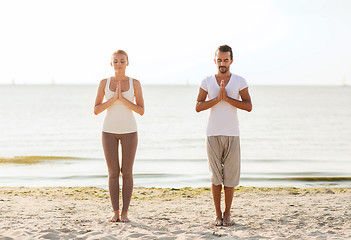 Image showing smiling couple making yoga exercises outdoors