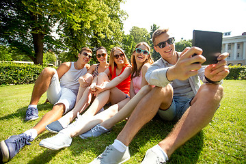 Image showing smiling friends with tablet pc computer in park