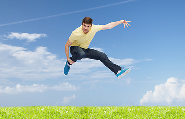 Image showing smiling young man jumping in air