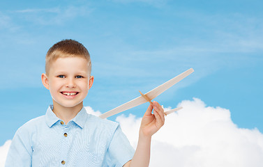 Image showing smiling little boy holding a wooden airplane model