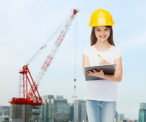 Image showing smiling little girl in hardhat with clipboard