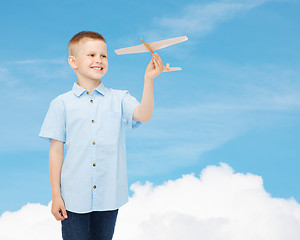 Image showing smiling little boy holding a wooden airplane model