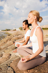 Image showing smiling couple making yoga exercises outdoors