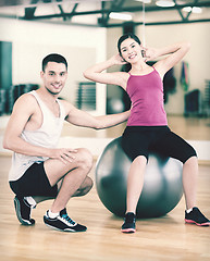 Image showing male trainer with woman doing crunches on the ball