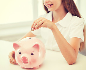 Image showing smiling child putting coin into big piggy bank