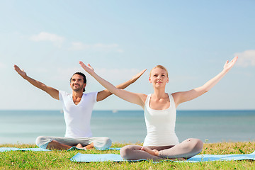 Image showing smiling couple making yoga exercises outdoors