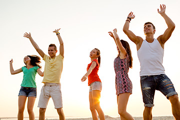 Image showing smiling friends dancing on summer beach