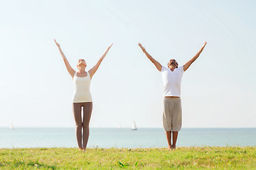 Image showing smiling couple making yoga exercises outdoors