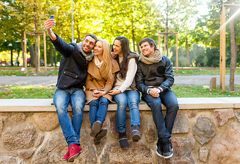 Image showing smiling friends with smartphones in city park