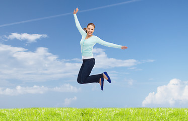 Image showing smiling young woman jumping in air