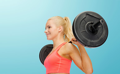 Image showing smiling sporty woman exercising with barbell