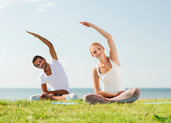 Image showing smiling couple making yoga exercises outdoors