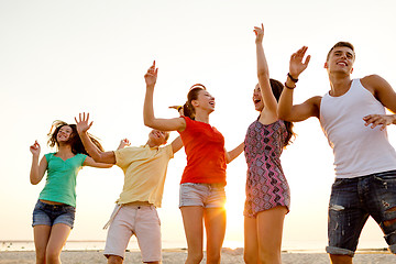 Image showing smiling friends dancing on summer beach