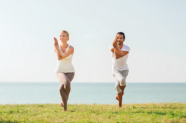 Image showing smiling couple making yoga exercises outdoors