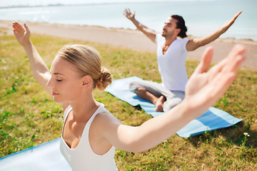 Image showing smiling couple making yoga exercises outdoors