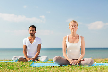 Image showing smiling couple making yoga exercises outdoors