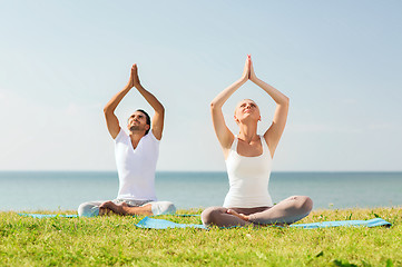 Image showing smiling couple making yoga exercises outdoors