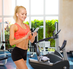 Image showing smiling sporty woman with smartphone and earphones