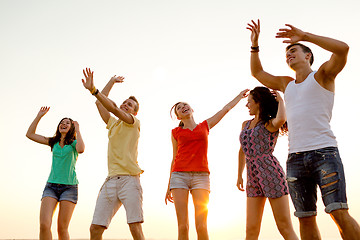 Image showing smiling friends dancing on summer beach