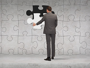 Image showing businessman in suit setting piece of puzzle