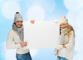 Image showing smiling couple in winter clothes with blank board