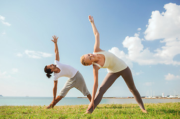 Image showing smiling couple making yoga exercises outdoors