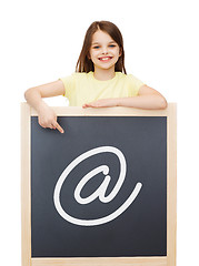 Image showing smiling little girl pointing finger to blackboard