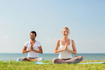 Image showing smiling couple making yoga exercises outdoors