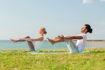 Image showing smiling couple making yoga exercises outdoors