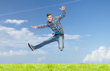 Image showing smiling young man jumping in air