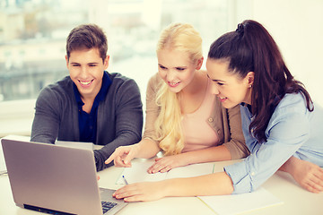 Image showing three smiling students with laptop and notebooks