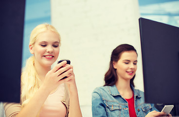 Image showing two teens with smartphones in computer class