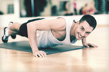 Image showing smiling man doing push-ups in the gym