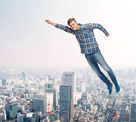 Image showing smiling young man jumping in air