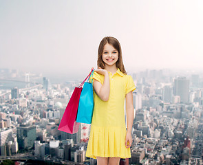 Image showing smiling little girl in dress with shopping bags