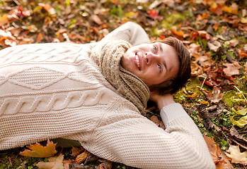Image showing close up of smiling young man lying in autumn park