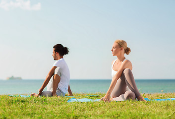 Image showing smiling couple making yoga exercises outdoors