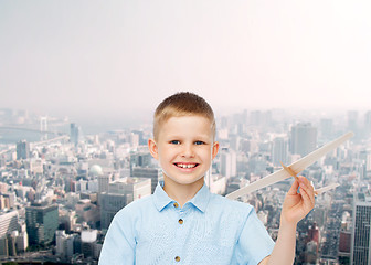 Image showing smiling little boy holding a wooden airplane model