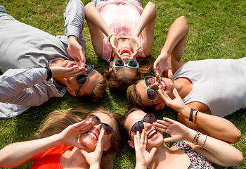 Image showing group of smiling friends lying on grass outdoors