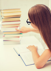 Image showing little student girl in eyeglasses with many books