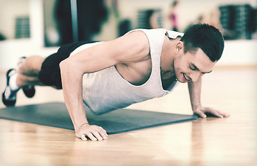 Image showing smiling man doing push-ups in the gym