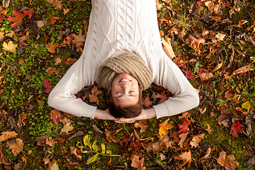 Image showing smiling young man lying on ground in autumn park