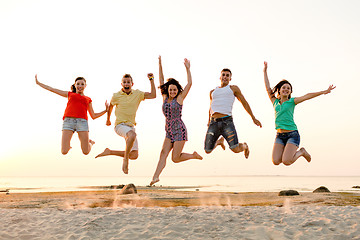 Image showing smiling friends dancing and jumping on beach