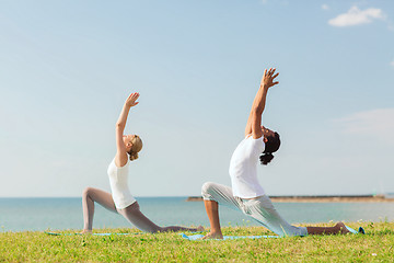 Image showing smiling couple making yoga exercises outdoors