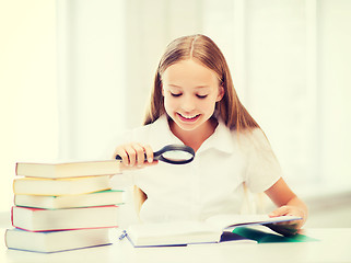 Image showing girl reading book with magnifier at school