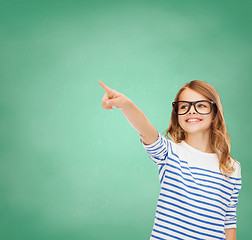 Image showing cute little girl in eyeglasses pointing in the air