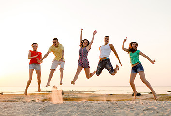 Image showing smiling friends dancing and jumping on beach