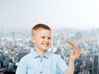 Image showing smiling little boy holding a wooden airplane model