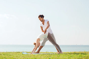 Image showing smiling couple making yoga exercises outdoors