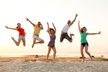 Image showing smiling friends dancing and jumping on beach